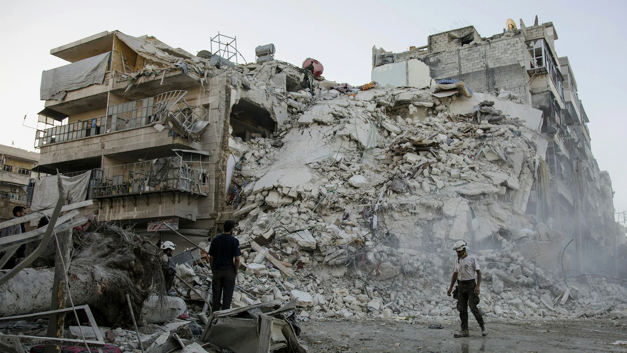 Members of the Syrian Civil Defence, known as the White Helmets, search for victims amid the rubble of a destroyed building following reported air strikes in the rebel-held Qatarji neighbourhood of the northern city of Aleppo, on October 17, 2016. Dozens of civilians were killed as air strikes hammered rebel-held parts of Aleppo early morning, despite Western warnings of potential sanctions against Syria and Russia over attacks on the city. Both Russian and Syrian warplanes are carrying out air strikes over Aleppo in support of a major offensive by regime forces to capture rebel-held parts of the northern city. / AFP / KARAM AL-MASRI (Photo credit should read KARAM AL-MASRI/AFP/Getty Images)
