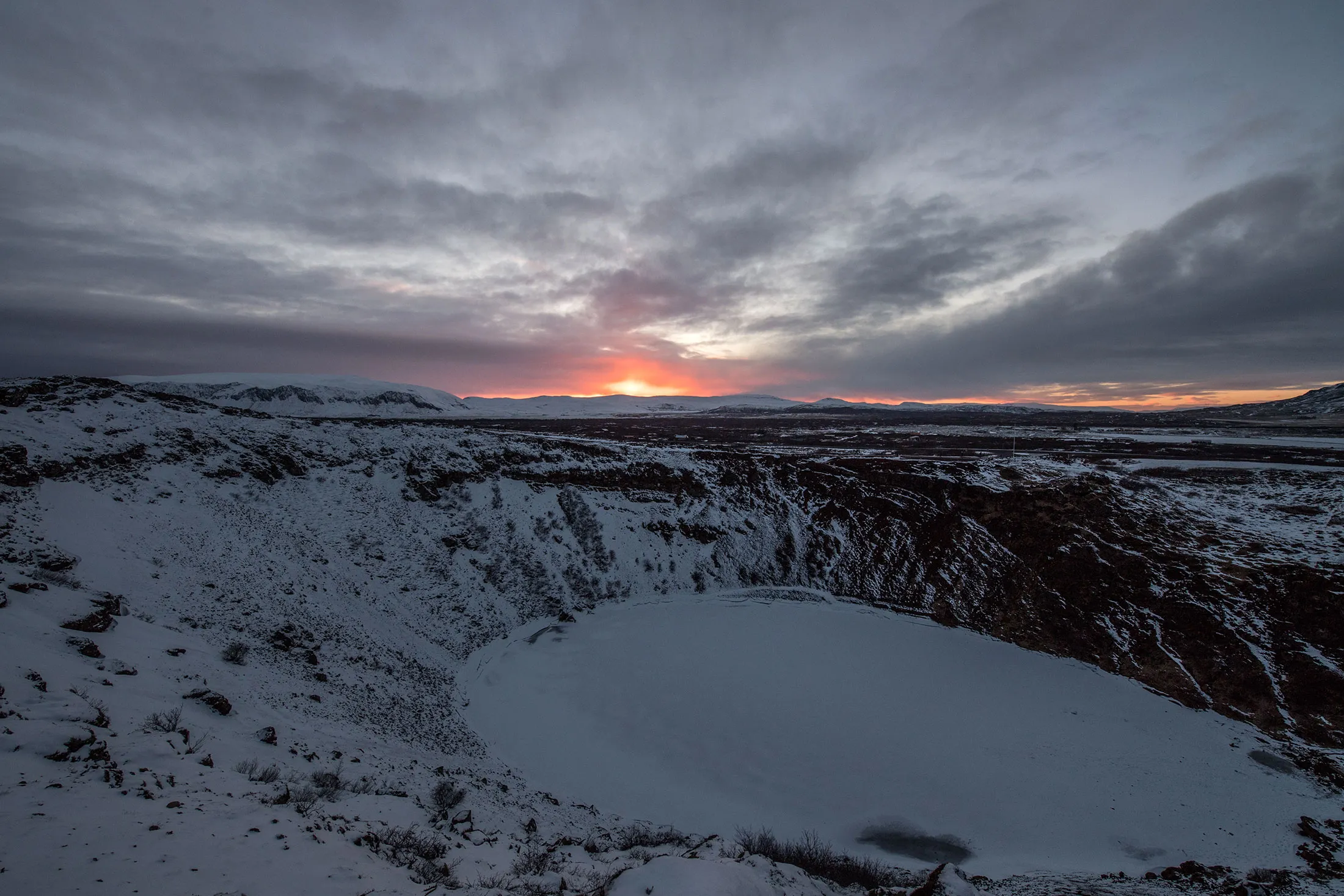 The sun sets behind the frozen volcanic crater lake Kerid, Iceland.&nbsp;