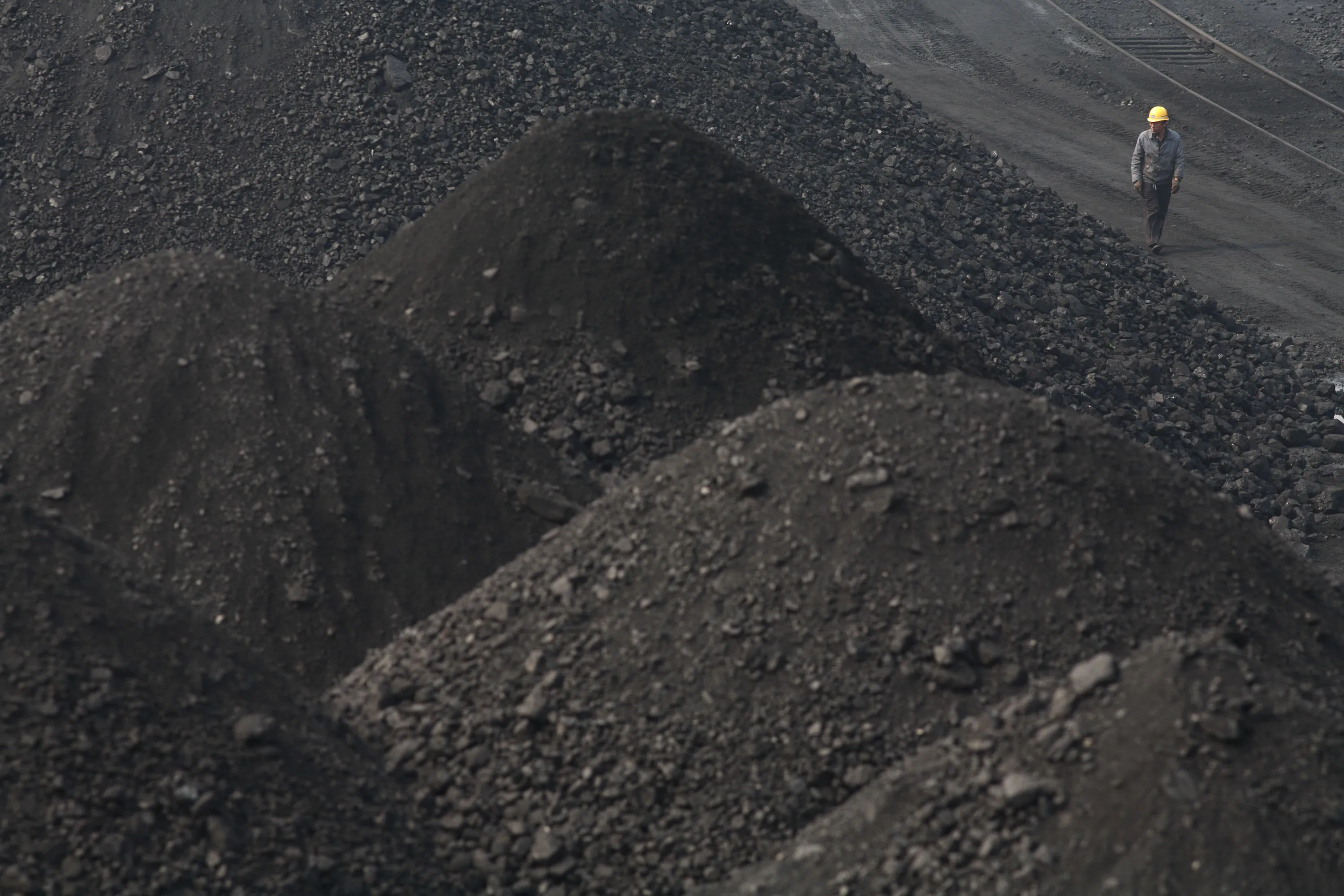 A man walks through piles of coal at a coal depot in Shanghai, China.
