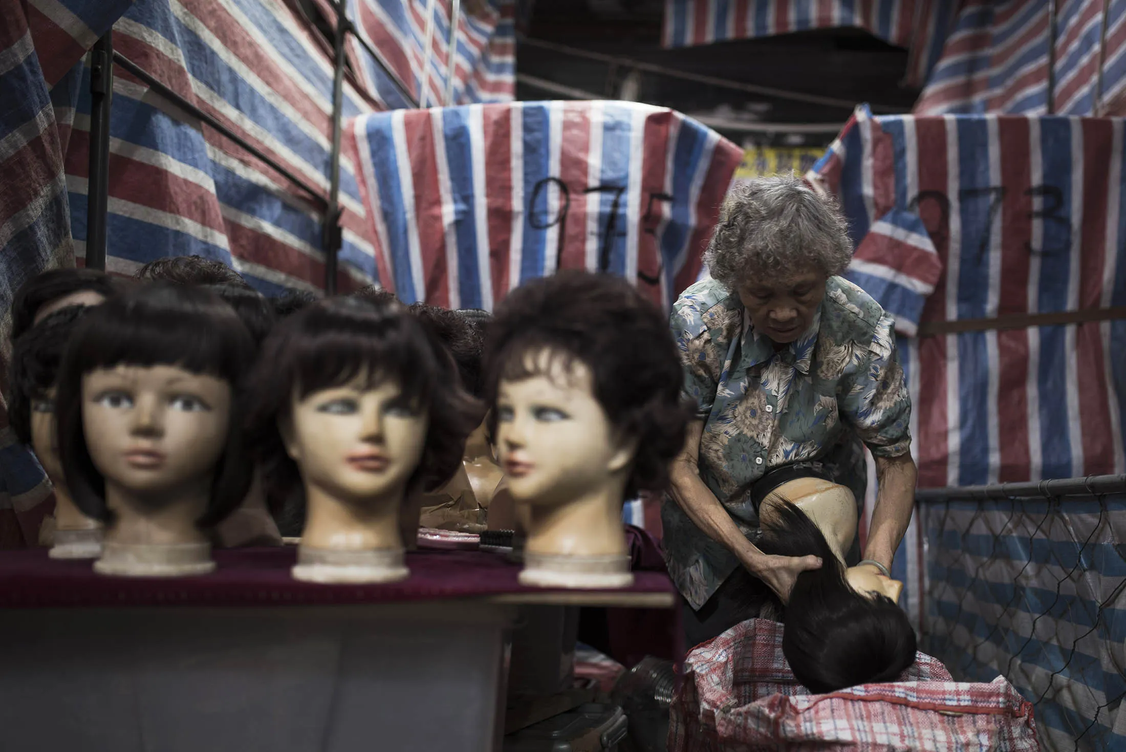 A vendor packs mannequin heads into a bag at a wig stall in a street market. FDI into China fell 5.8 percent in December from a year earlier to 77 billion yuan ($12 billion), while outbound non-financial investment climbed 6.1 percent.
