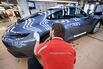 An employee performs a quality check on a Porsche 911 luxury automobile. 
