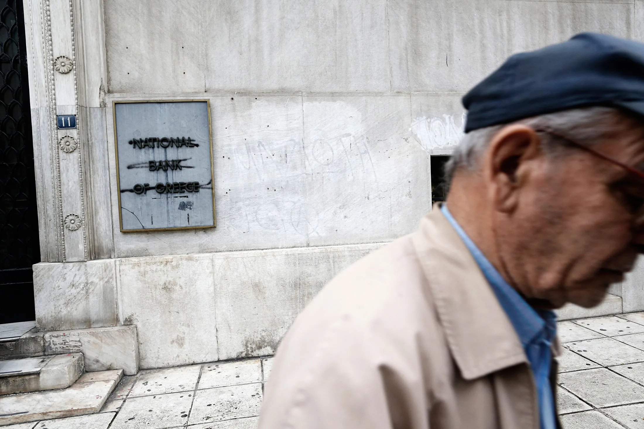 A pensioner passes a main branch of the National Bank of Greece in Thessaloniki.
