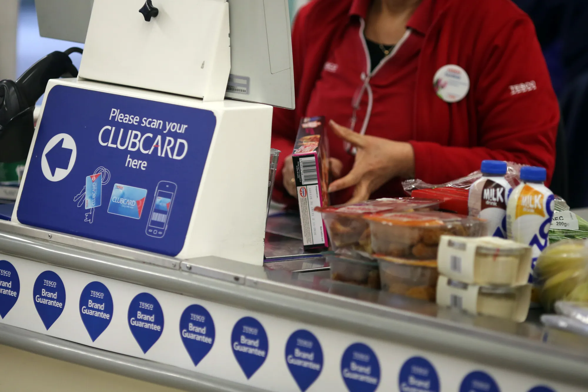 An employee takes an item from the conveyor belt at a Tesco supermarket.