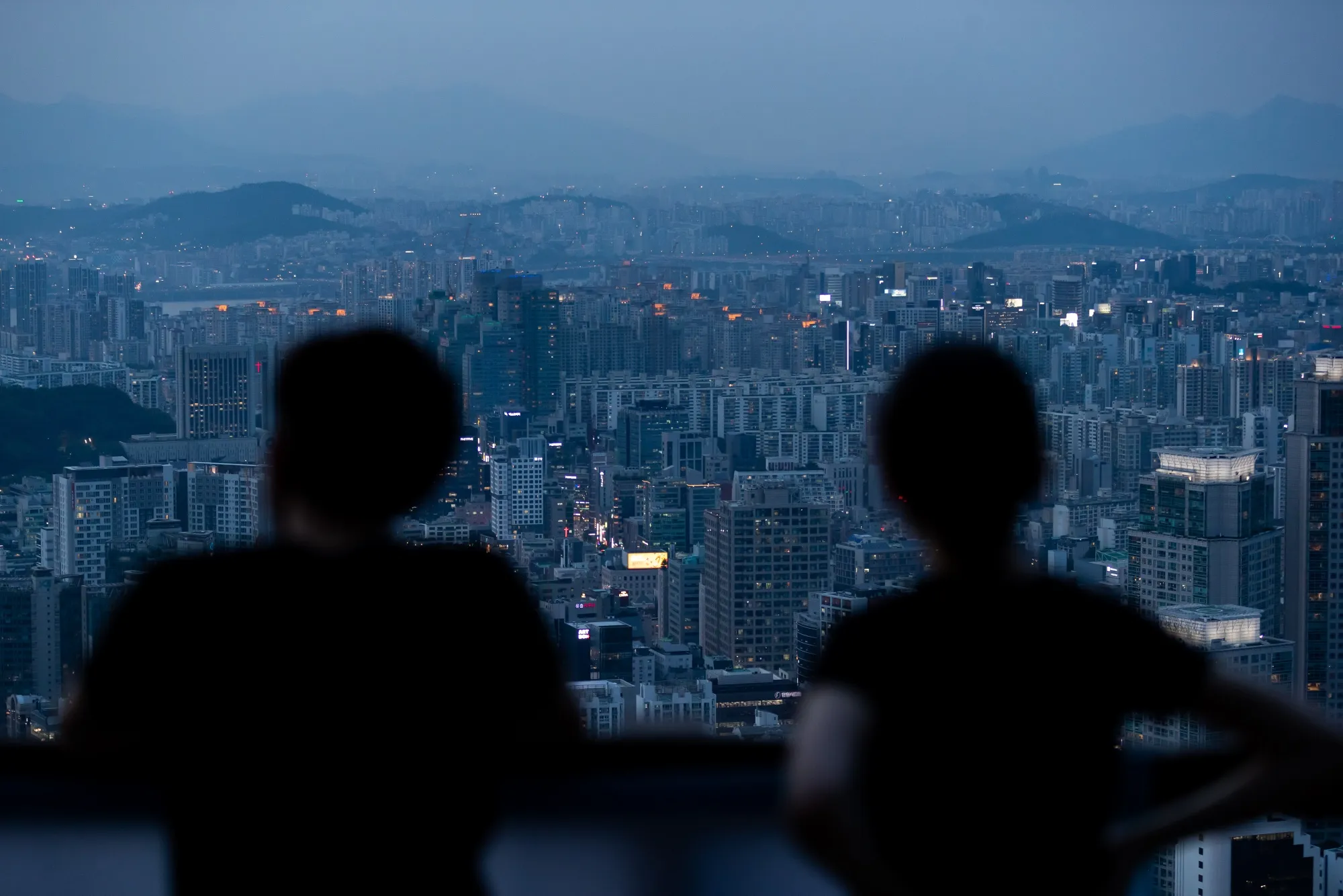 People are silhouetted at an observation deck of Woomyeon mountain in Seoul.