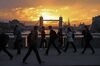 Commuters walk across London Bridge against a backdrop of Tower Bridge during sunrise in London, U.K.