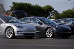 People look inside the trunk of a Tesla Inc. Model 3 electric vehicle at the company's delivery center in Marina Del Rey, California, U.S.