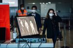 A monitor displays a thermal camera image of travelers wearing protective face masks at Charles de Gaulle Airport.