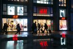 Pedestrians pass an illuminated Hennes & Mauritz AB (H&M) clothing fashion store in Berlin.