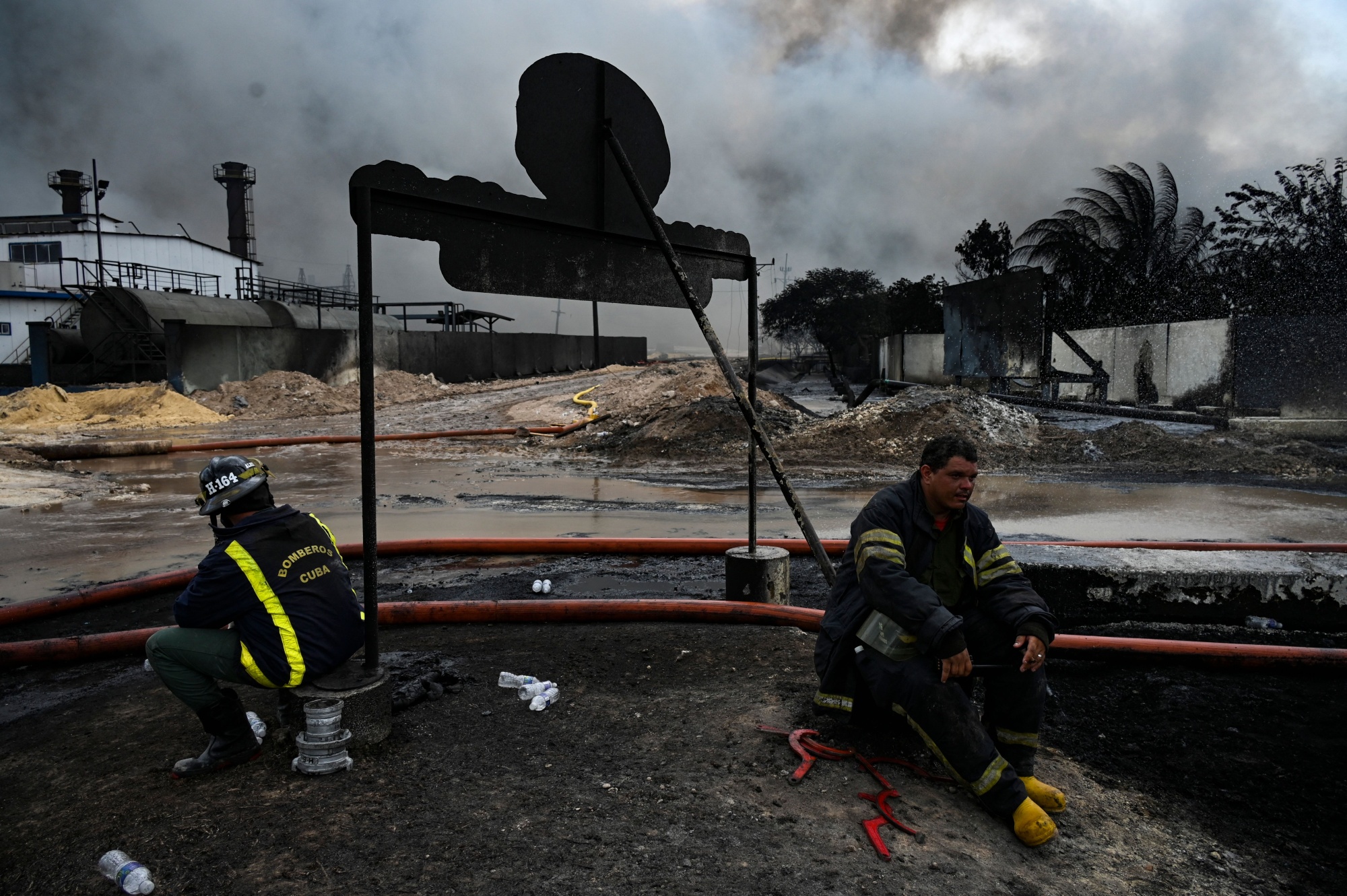 Firefighters rest in an area where a massive fire at a fuel depot occurred in Matanzas, Cuba, on August 9.