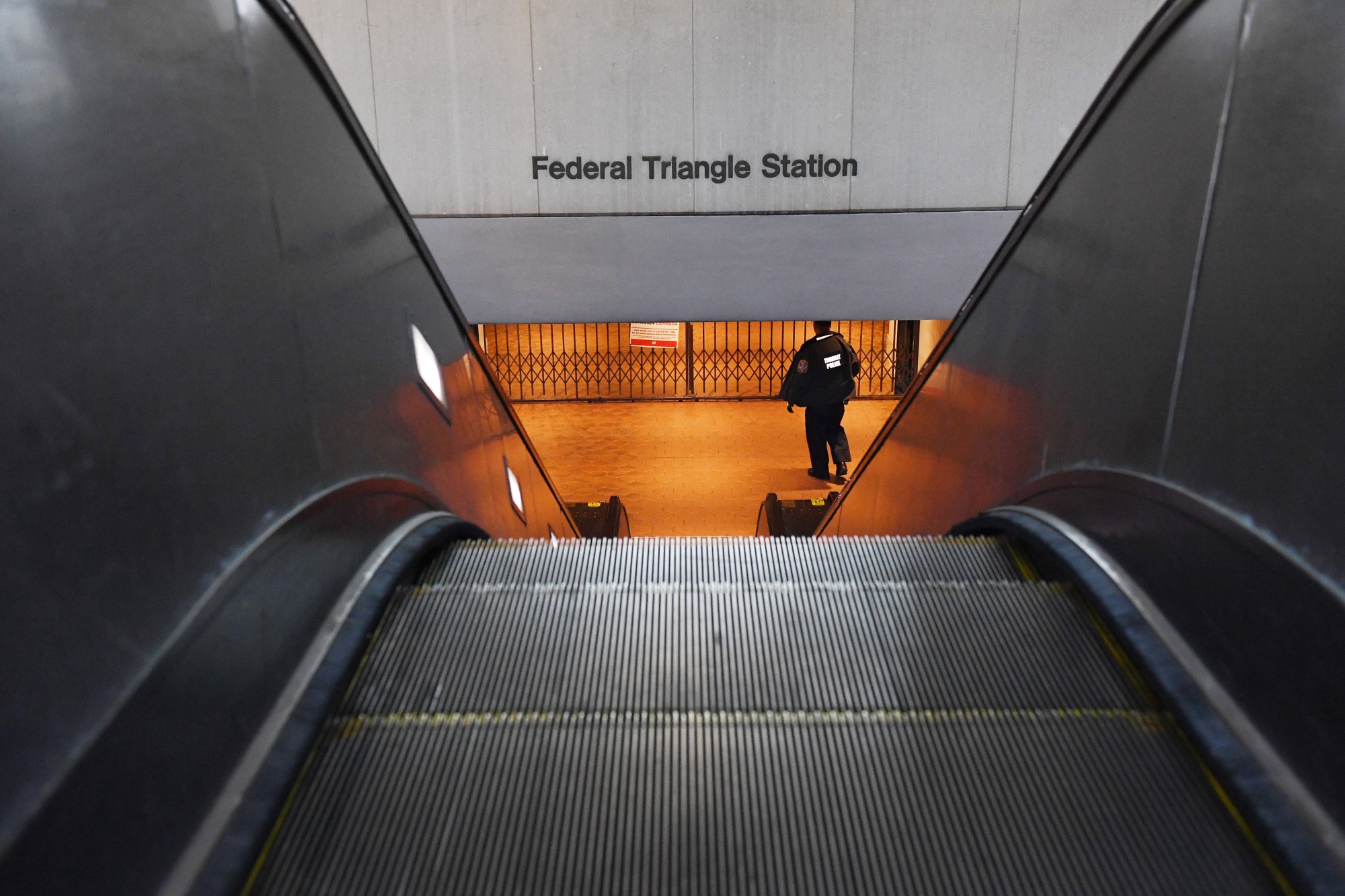 A transit officer is seen at a closed Federal Triangle Station in Washington, DC. The region’s public transit agency released a plan to close 19 stations, among other cuts, unless federal aid provides some financial&nbsp;relief.&nbsp;