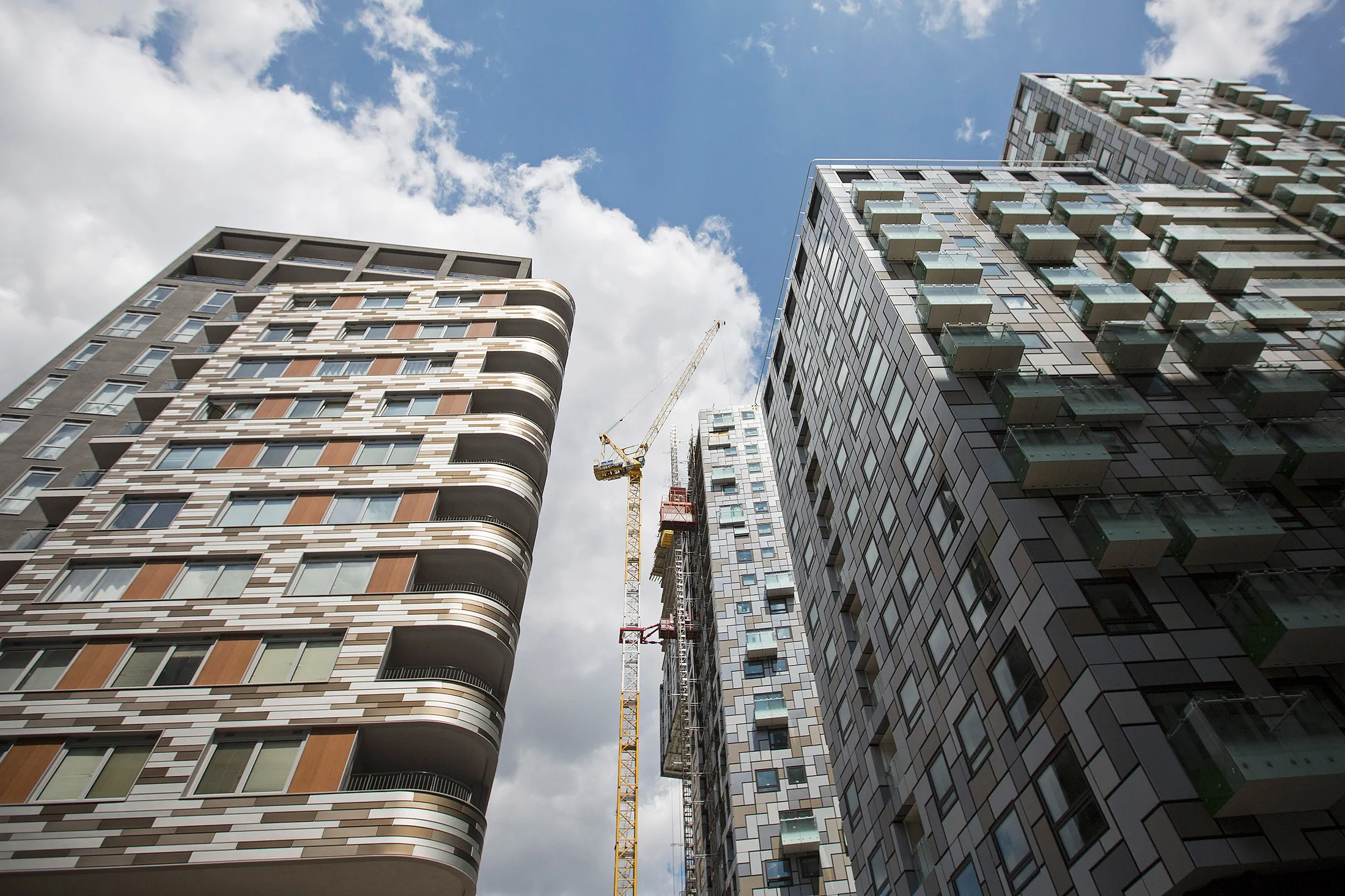 A crane stands alongside a residential apartment under construction in the Lincoln Plaza area, developed by Galliard Homes, in the Canary Wharf business, financial and shopping district, in London, U.K., on Thursday, May 21, 2015. Developers are seeking to appeal to foreign buyers, who favor apartments, with high-rise, high-volume projects, particularly in east London.
