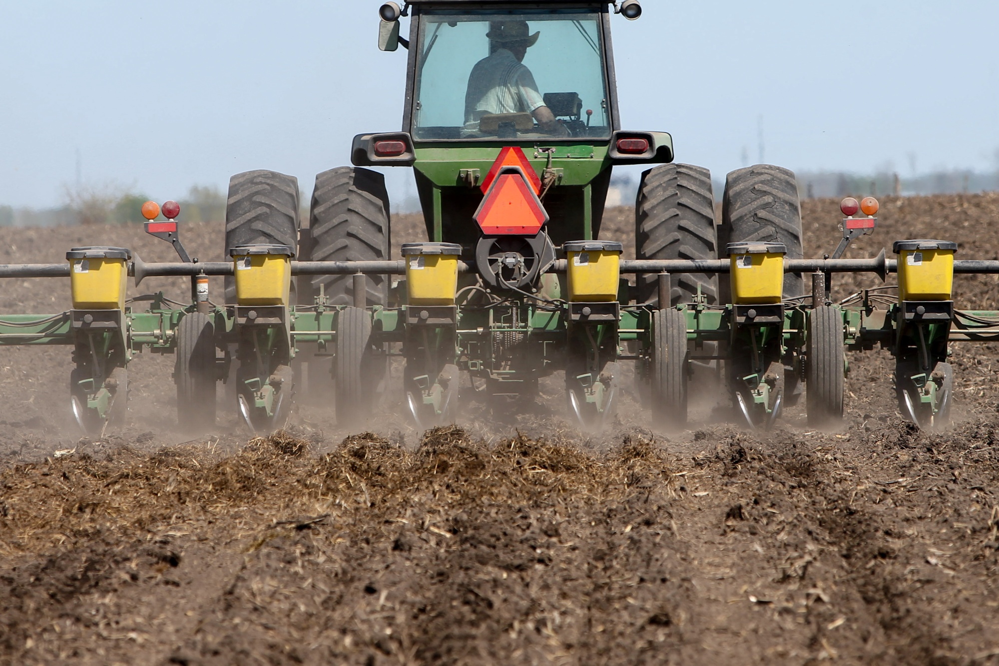 A worker uses a tractor to plant soybeans at Double G Angus Farms in Tiffin, Iowa.