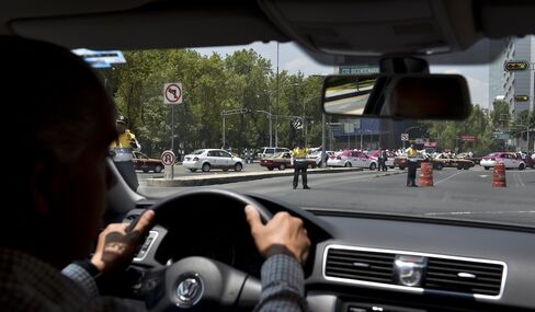 An Uber driver is diverted by traffic police as taxi drivers cross the avenue during a protest against the company, in Mexico City, on May 25, 2015.