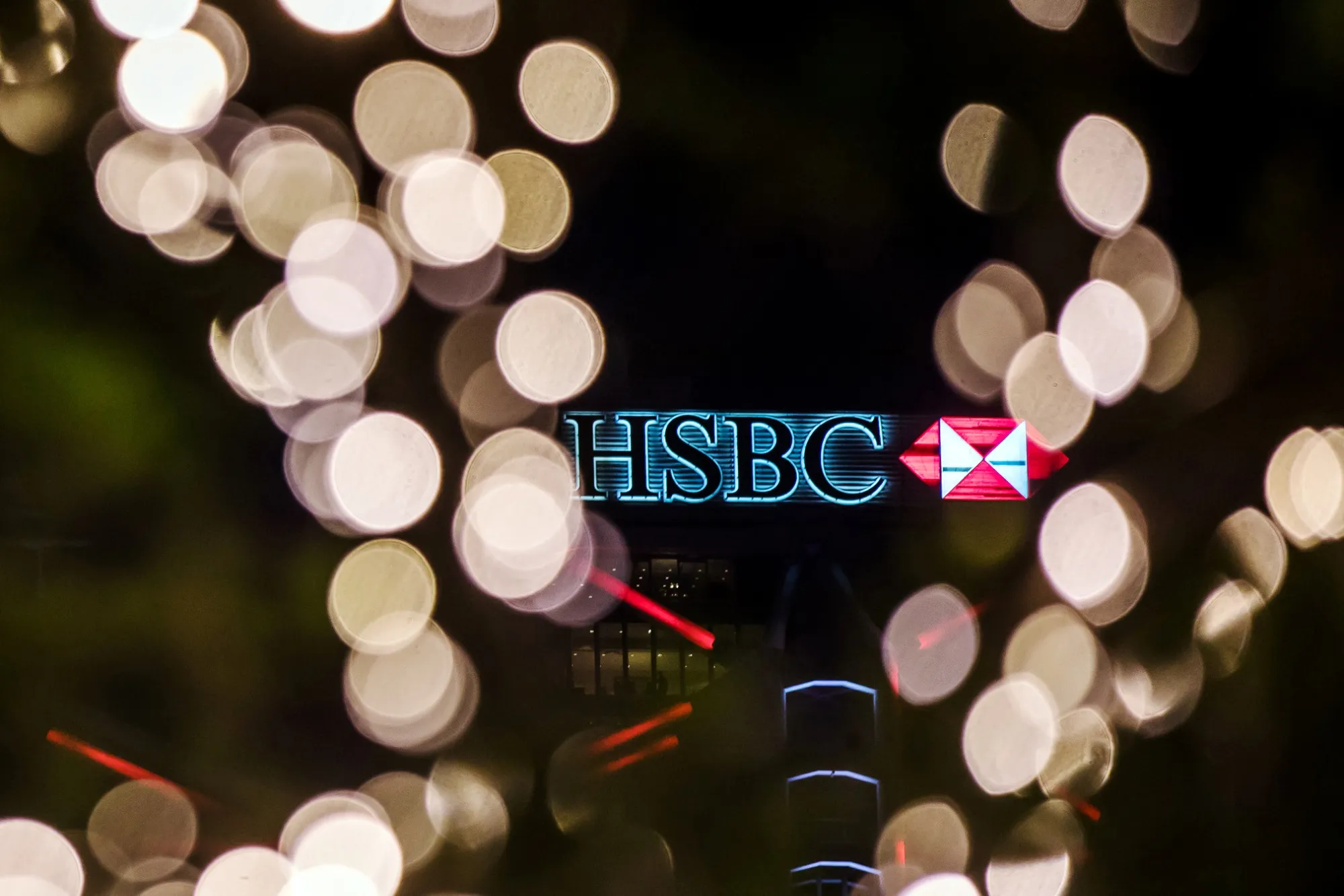 Signage is illuminated atop the HSBC Holdings Plc headquarters building at night in Hong Kong, China, on Thursday, July 25, 2019. HSBC is scheduled to release interim earnings results on Aug. 5.