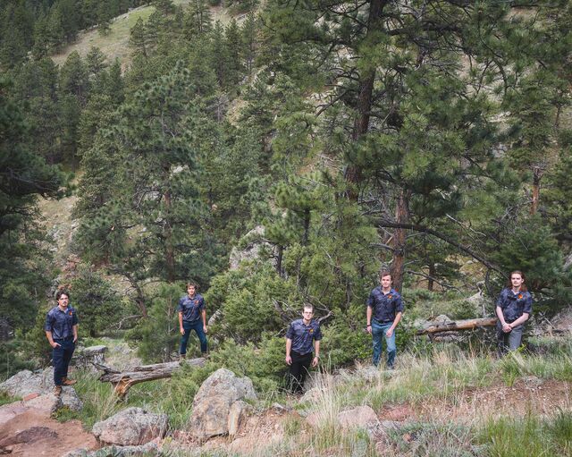 Five members of the Flatiron Fire Defense team posing for a photo in a juniper forest above Boulder.