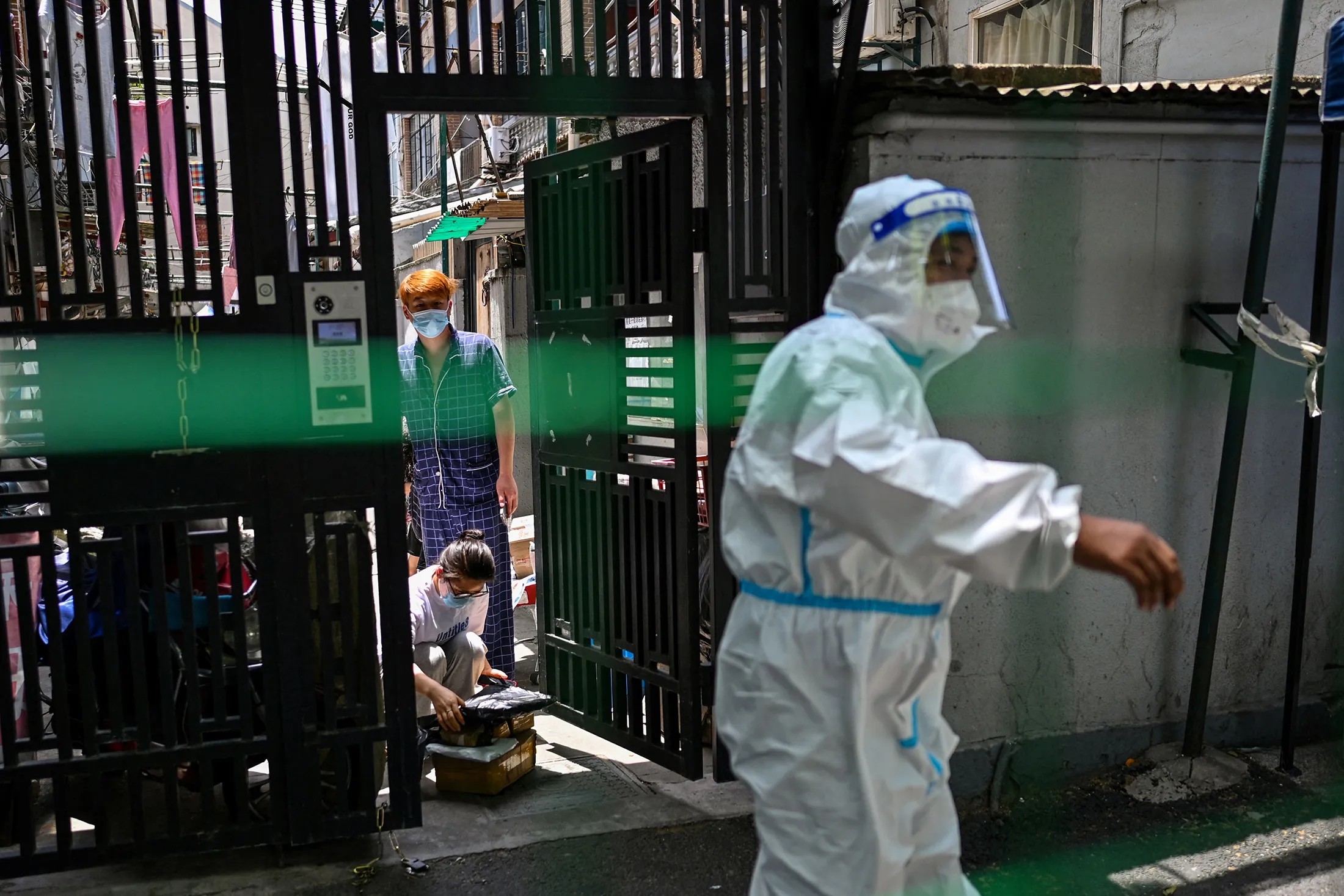 Residents collect their delivery order beyond fencing securing a residential area under Covid-19 lockdown in the Xuhui district of Shanghai on June 8.