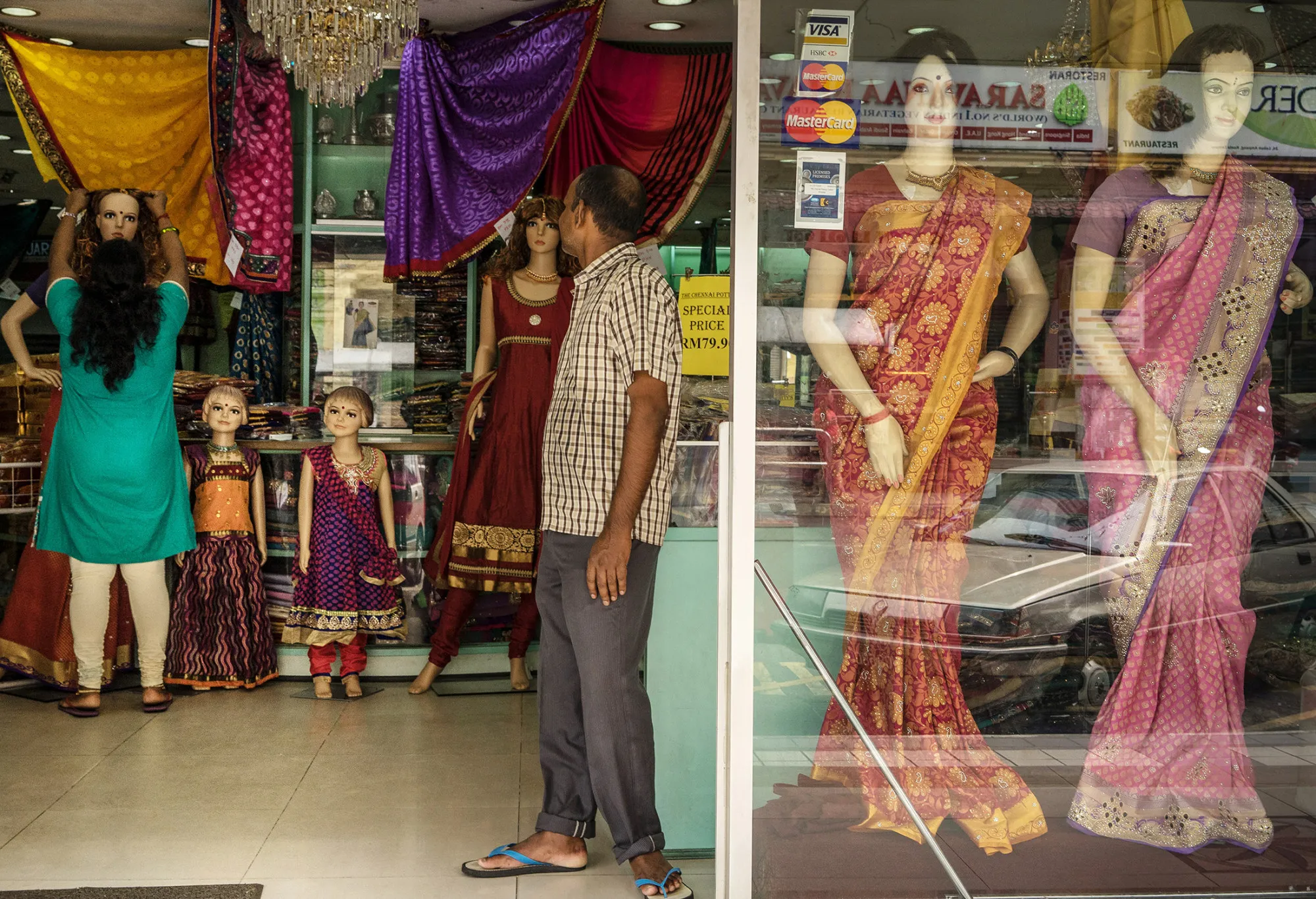 A store assistant stands at the entrance of a saree store in Kuala Lumpur, Malaysia.
