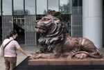 A woman touches the paws of a bronze lion statue, restored after being vandalized in Hong Kong’s protests.