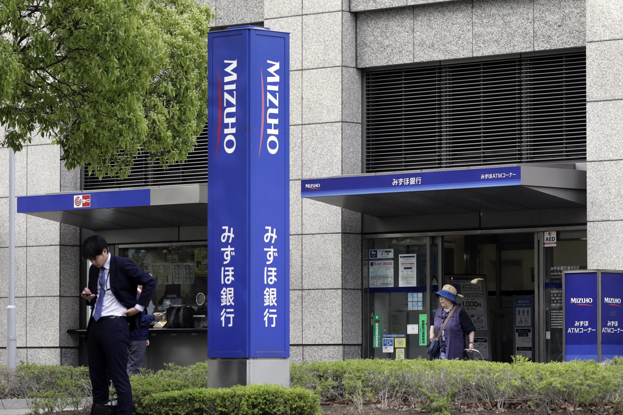 Pedestrians walk past a Mizuho Bank branch in Tokyo.