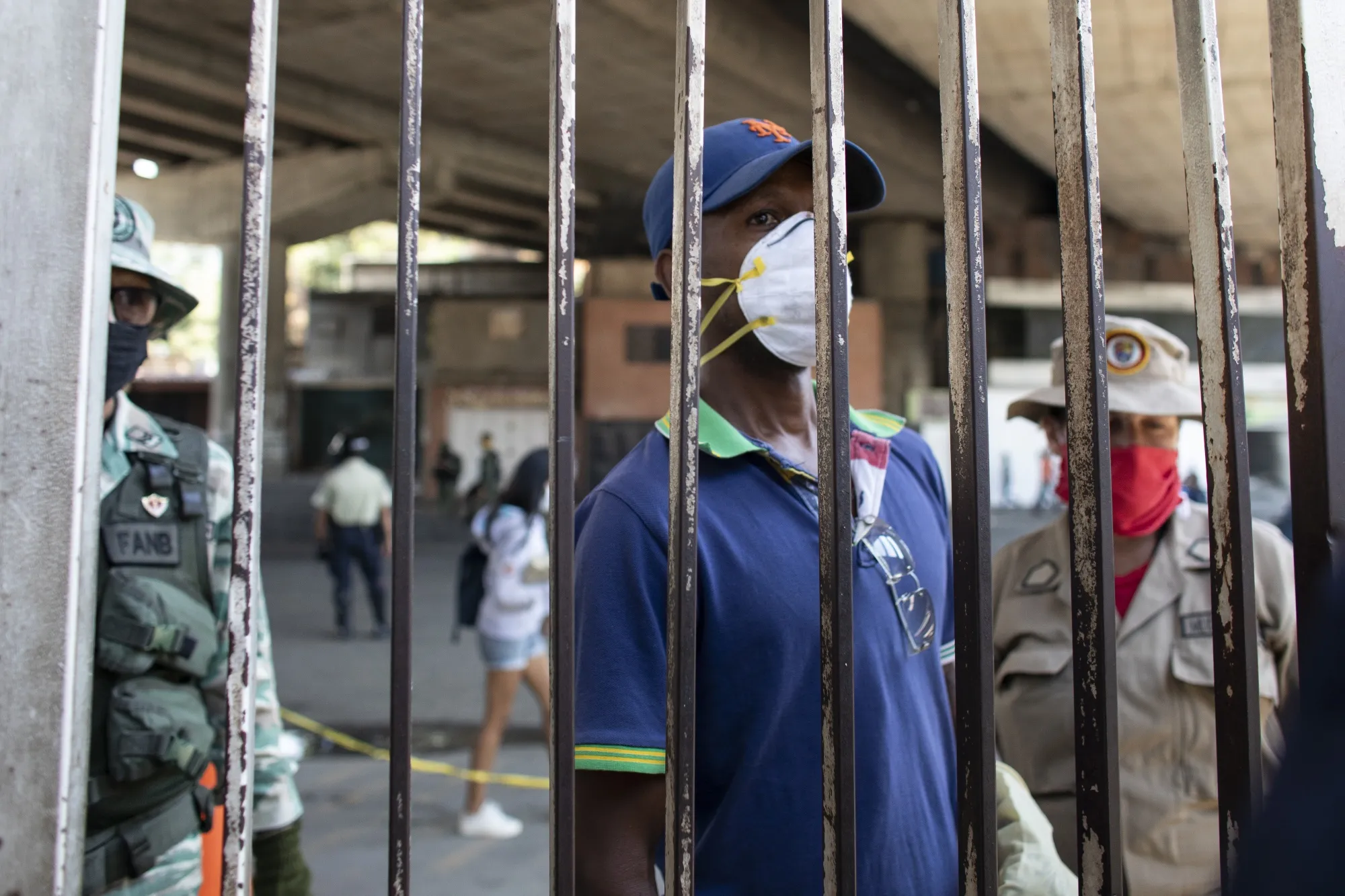 A person waits behind a security gate outside of a Caracas hospital in April 2020.