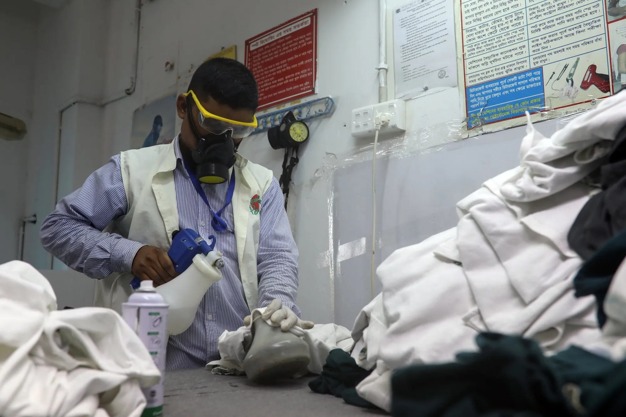 A worker in protective gear cleans spots from finished products at a garment factory in Gazipur, Bangladesh.