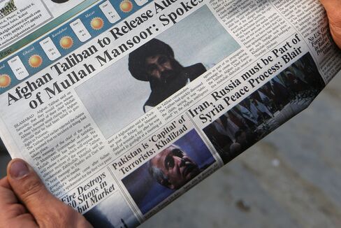 A man reads a newspaper in Kabul with a photo of the Afghan Taliban leader Mullah Mansour, center, in this Dec. 6, 2015 photo.