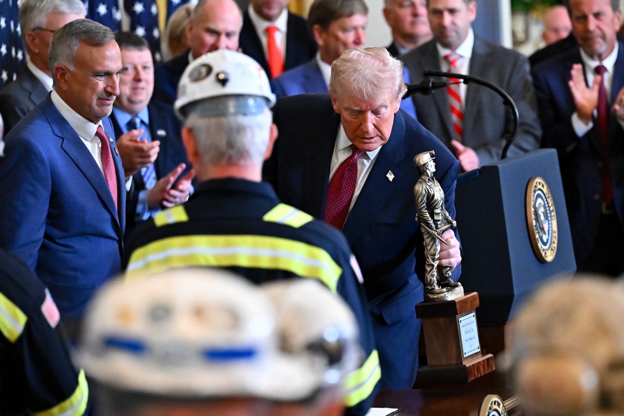 Jim Grech, president and chief executive officer of Peabody Energy Corp., left, watches as US President Donald Trump holds a trophy during a 