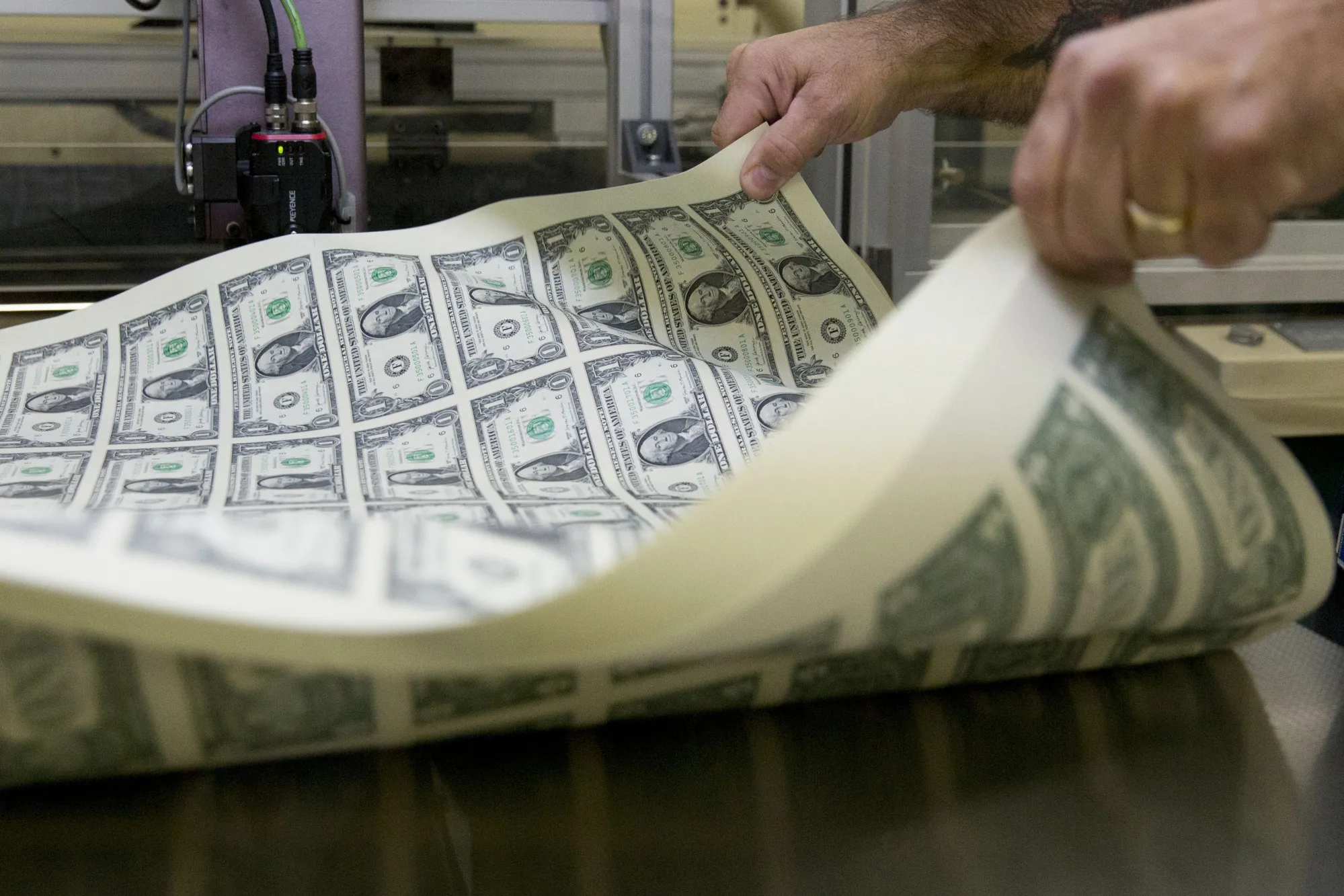 A pressman aerates a stack of 2017 50 subject uncut sheet of $1 dollar notes at the U.S. Bureau of Engraving and Printing in Washington, D.C., in 2017.&nbsp;