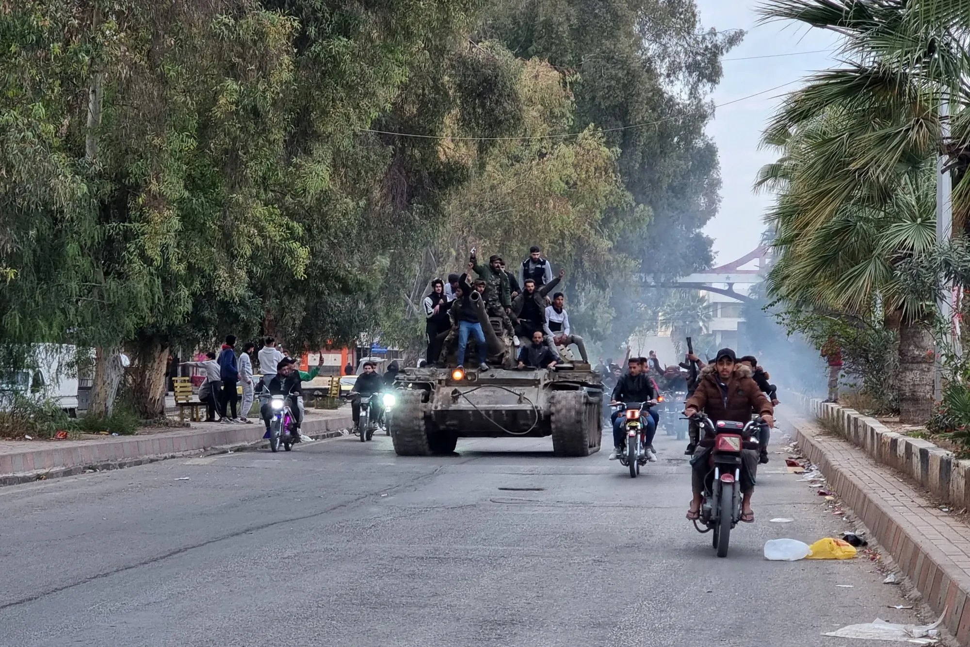 People ride a tank after the collapse of government forces in the city of Daraa on Dec. 7.