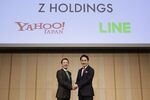 Kentaro Kawabe, president and chief executive officer of Z Holdings Corp., formerly known as Yahoo Japan, left, and Takeshi Idezawa, chief executive officer of Line Corp., shake hands as they pose for a photograph during a news conference in Tokyo.