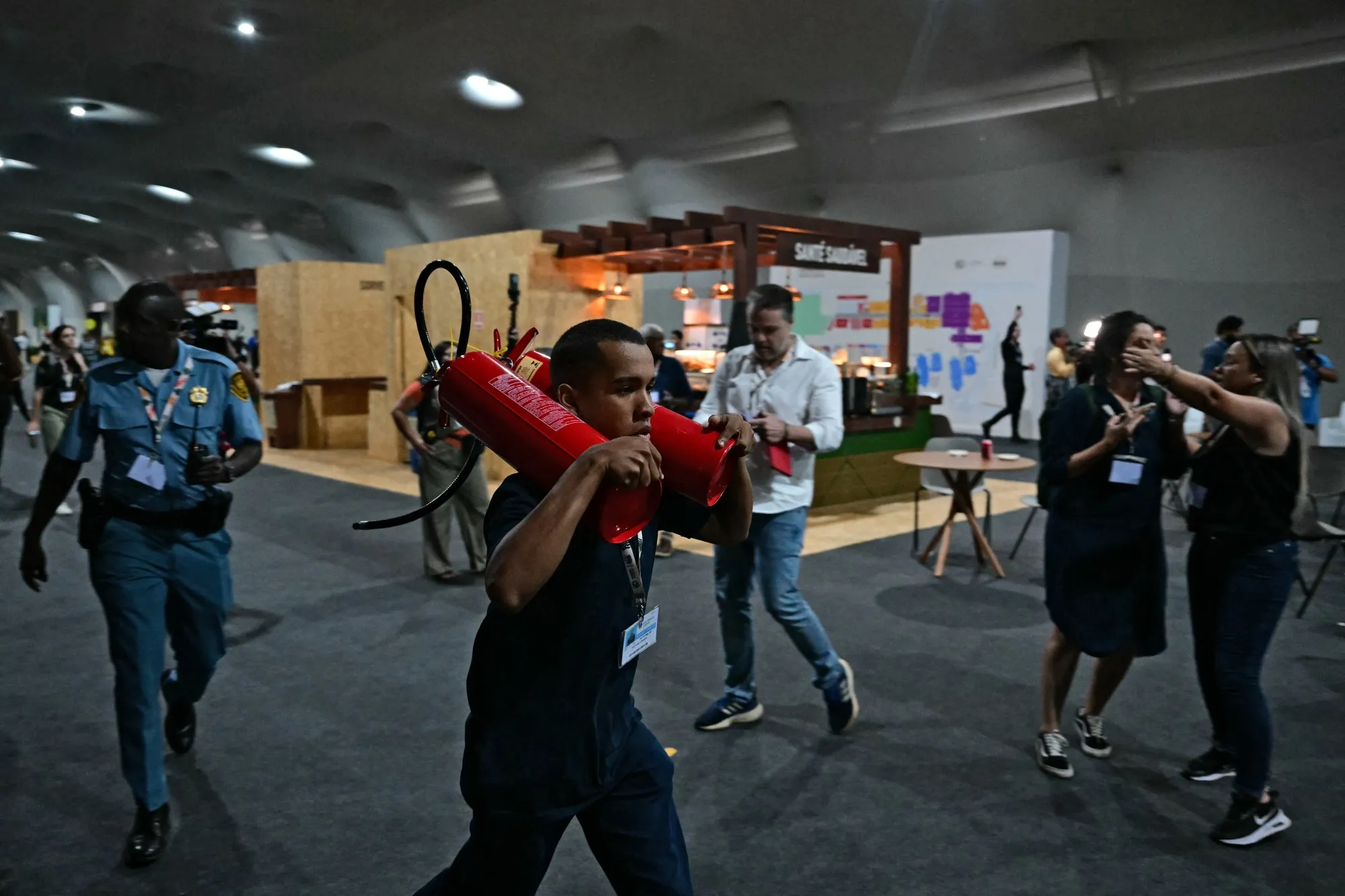 A worker runs carrying fire extinguishers towards a pavilion after a fire broke out at COP30 in Belem, Brazil.