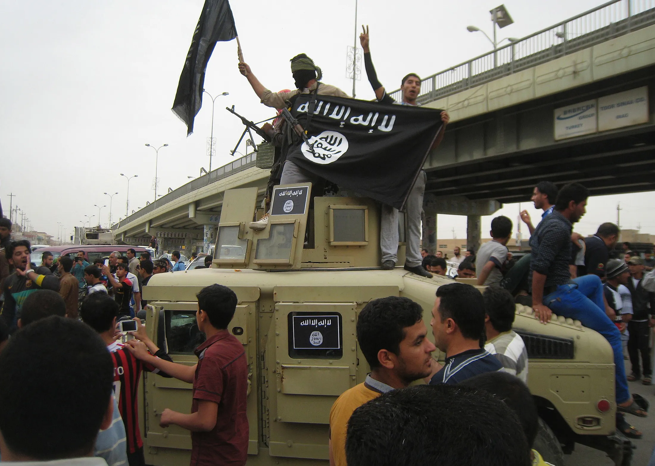 In this, March 30, 2014, file photo, Islamic State group militants hold up their flag as they patrol in a commandeered Iraqi military vehicle in Fallujah, 40 miles (65 kilometers) west of Baghdad, Iraq.

