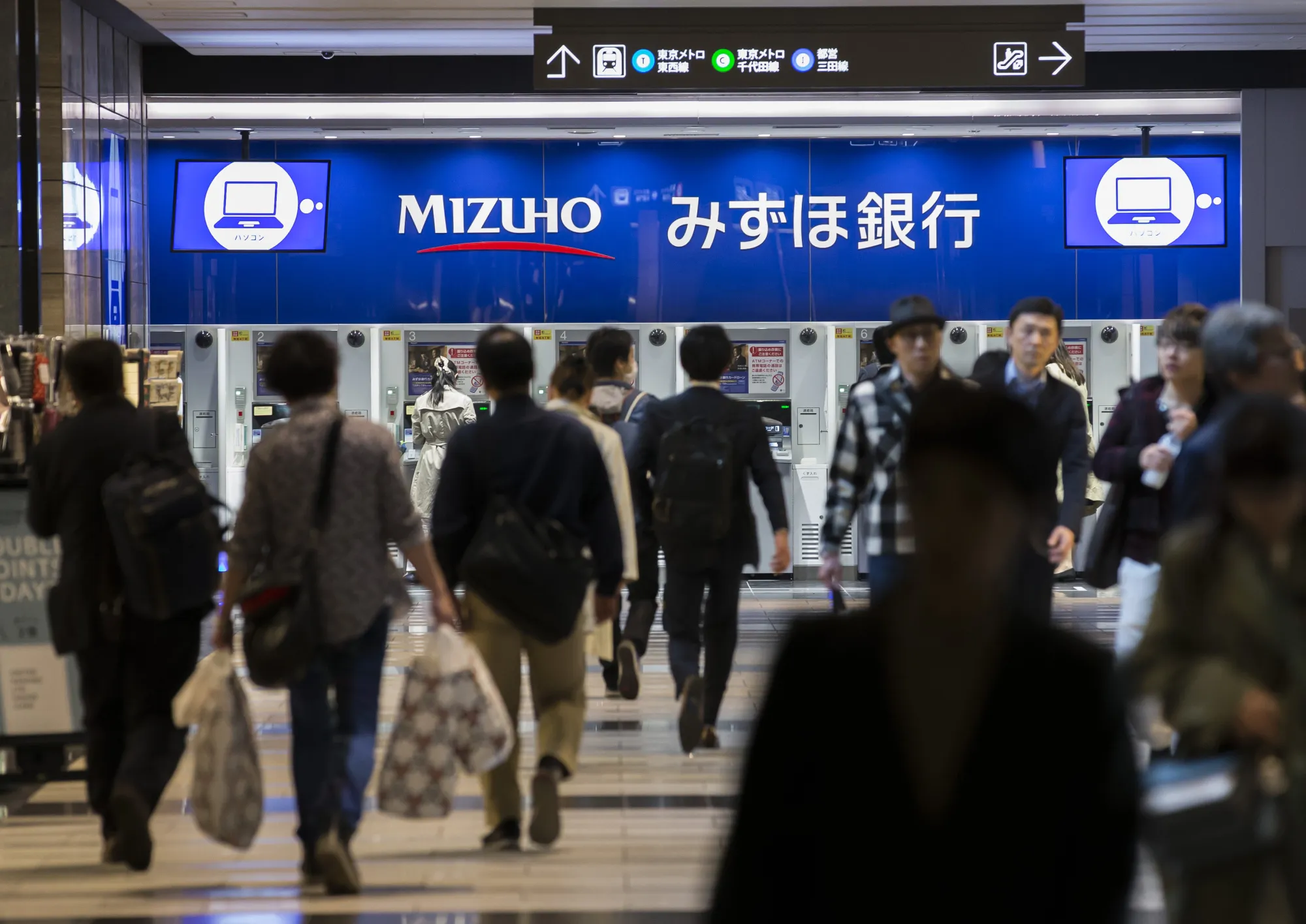 Pedestrians walk in front of Mizuho Bank Ltd.