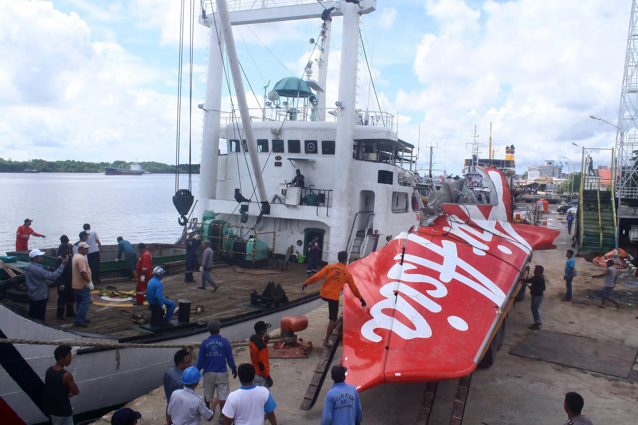 Workers load the tail of AirAsia flight 8501 onto a truck at Kumai sea port
