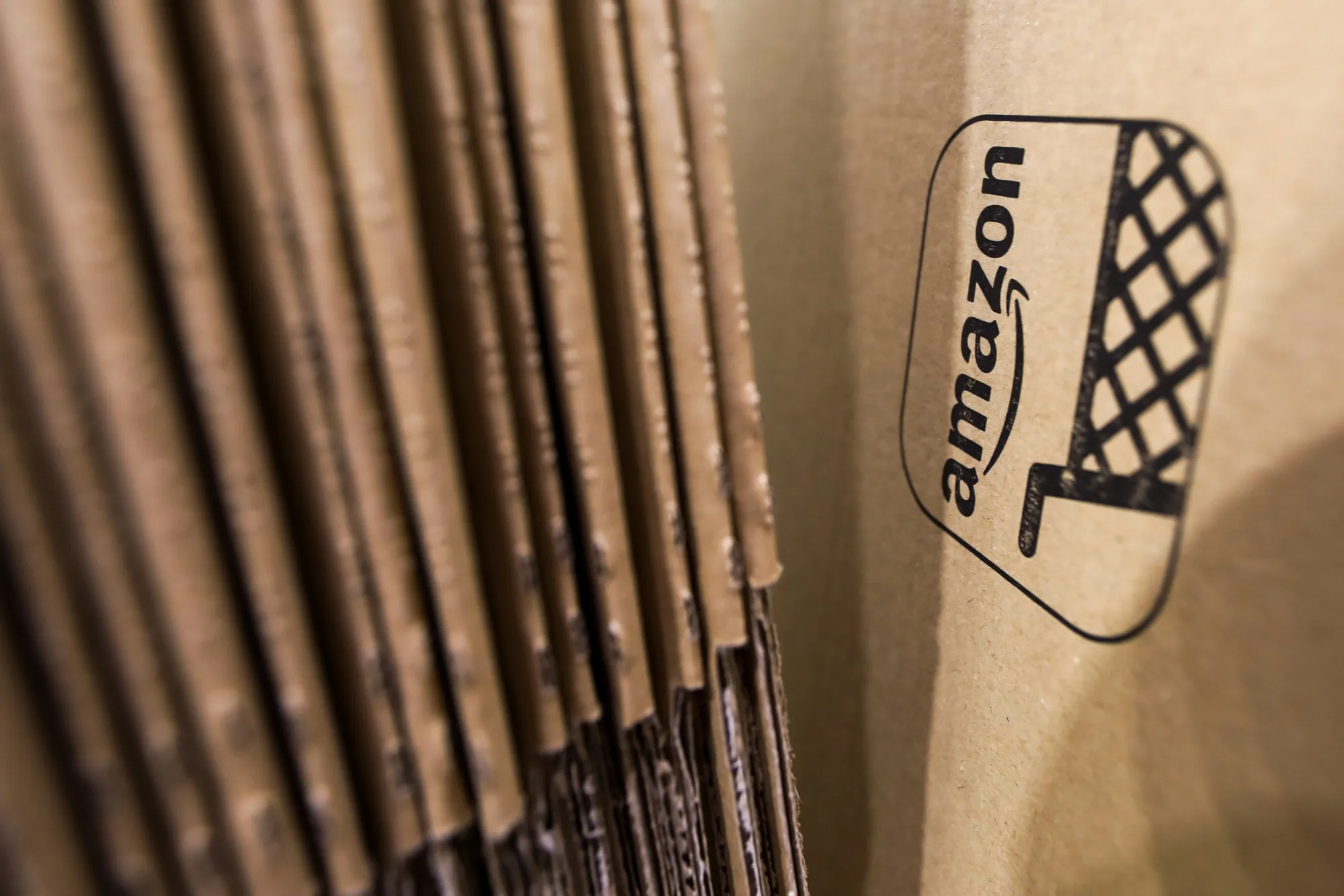 An Amazon.com Inc. logo sits on cardboard packaging at the company's fulfillment center in Peterborough, U.K., on Wednesday, Nov. 15, 2017. As Amazon's share of retail sales grows, its corporate stewardship is coming under greater scrutiny.