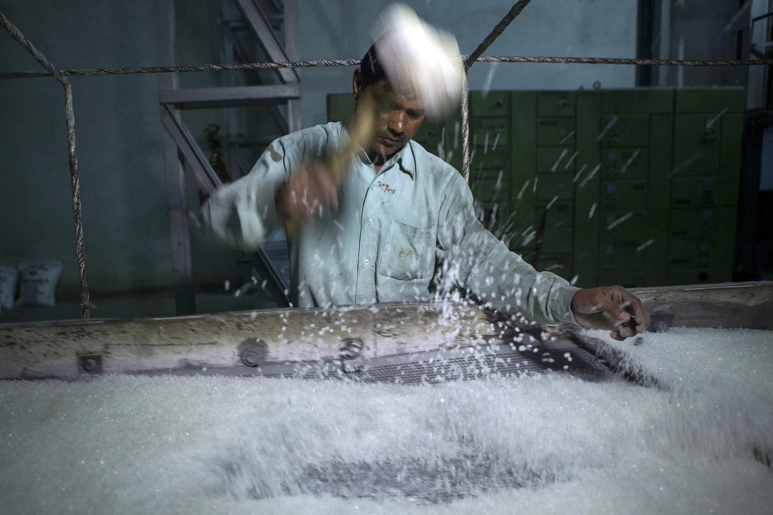 A worker breaks sugar crystals at a mill in India.