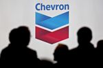 Attendees stand near Chevron signage during the World Gas Conference.