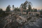 A two-story house continues to smolder following the McBride Fire in Ruidoso, New Mexico, on Thursday, April 14, 2022.   Authorities say firefighters have kept a wind-driven blaze from pushing further into a mountain community in the southern part of the state. (Justin Garcia /The Las Cruces Sun News via AP)