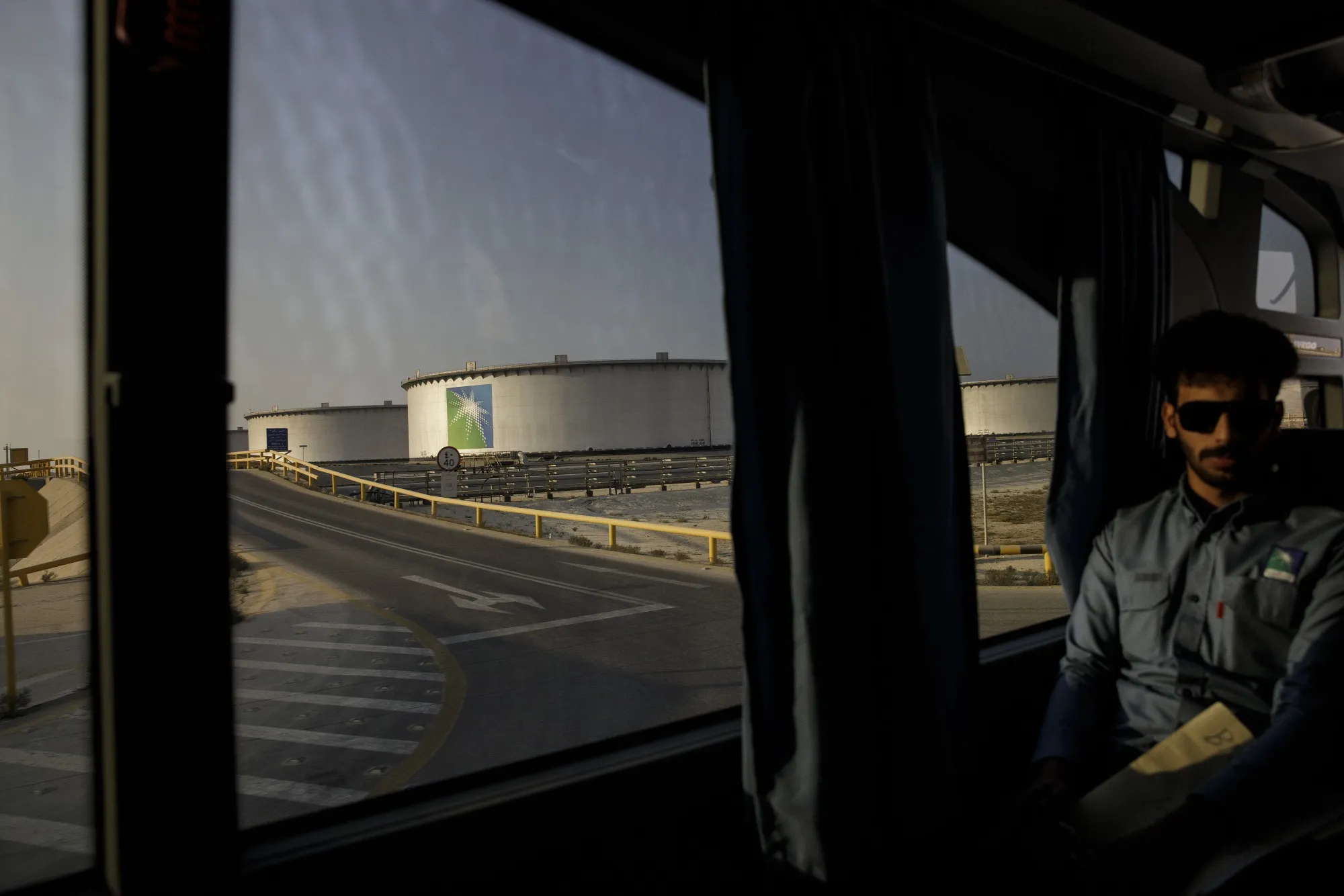 A bus transports employees past crude oil storage tanks in the Juaymah tank farm at Saudi Aramco's Ras Tanura oil refinery and terminal in Ras Tanura, Saudi Arabia.