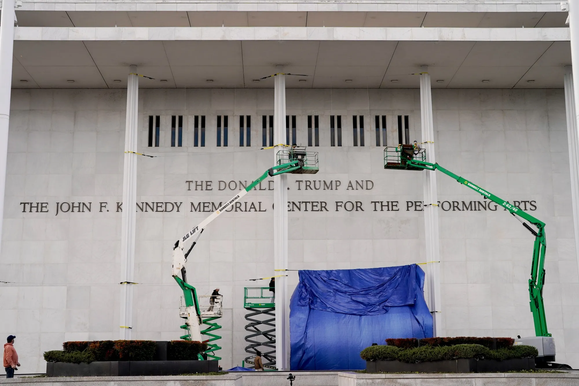 Workers affix signage adding US President Donald Trump's name on the facade of the Kennedy Center in Washington, DC on Dec. 19.