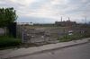 Same field behind a fence, no longer lush, with patches of ground dug up