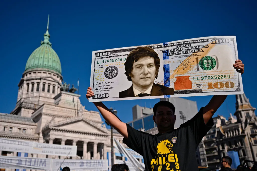 Un seguidor muestra una pancarta con un billete de cien dólares y una imagen de Javier Milei previo a su ceremonia de asunción en el Congreso Nacional en Buenos Aires el 10 de diciembre de 2023.