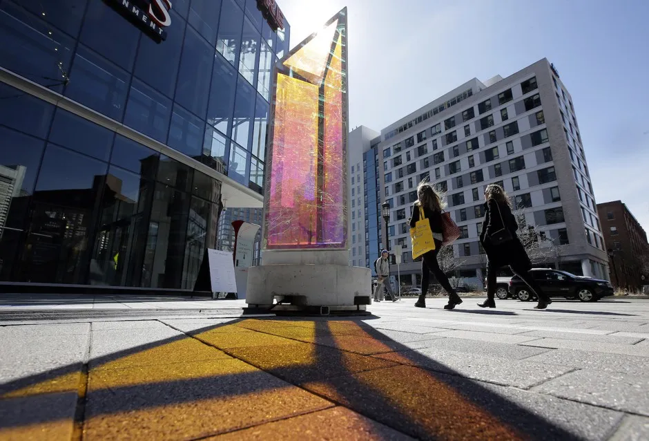 Passersby walk near an art installation in Boston's Seaport, where many tech companies are located.