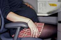Pregnant office worker at desk, mid section