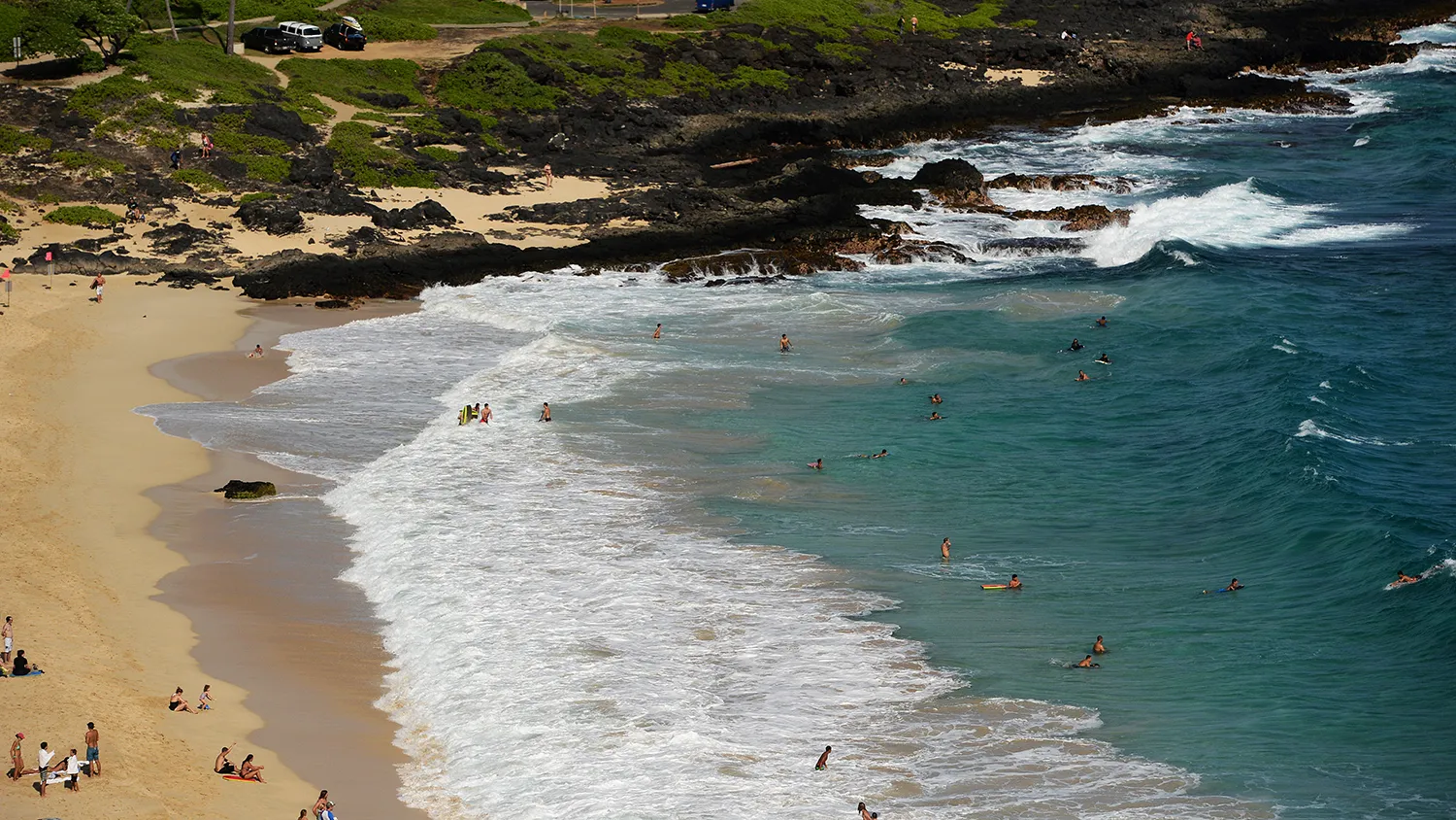 People enjoy a day out on a beach as US President Barack Obama's motorcade drives past in Hanauma Bay, Hawaii, on December 31, 2013.
