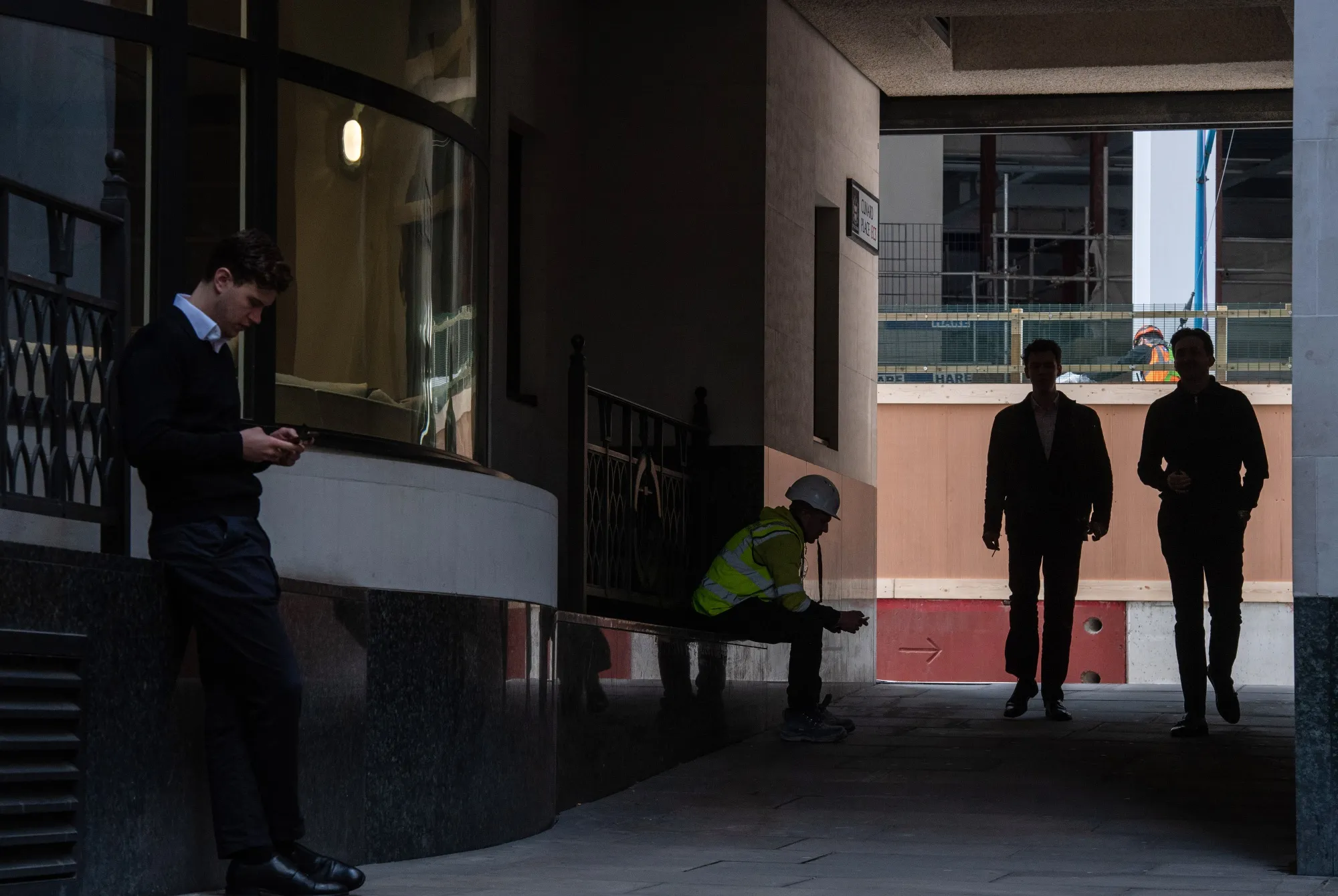 Office workers pass a construction worker in the City of London, U.K., on April 11.
