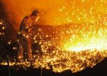 A worker pries up molten cast iron from a blast furnace at a Chinese steel plant.