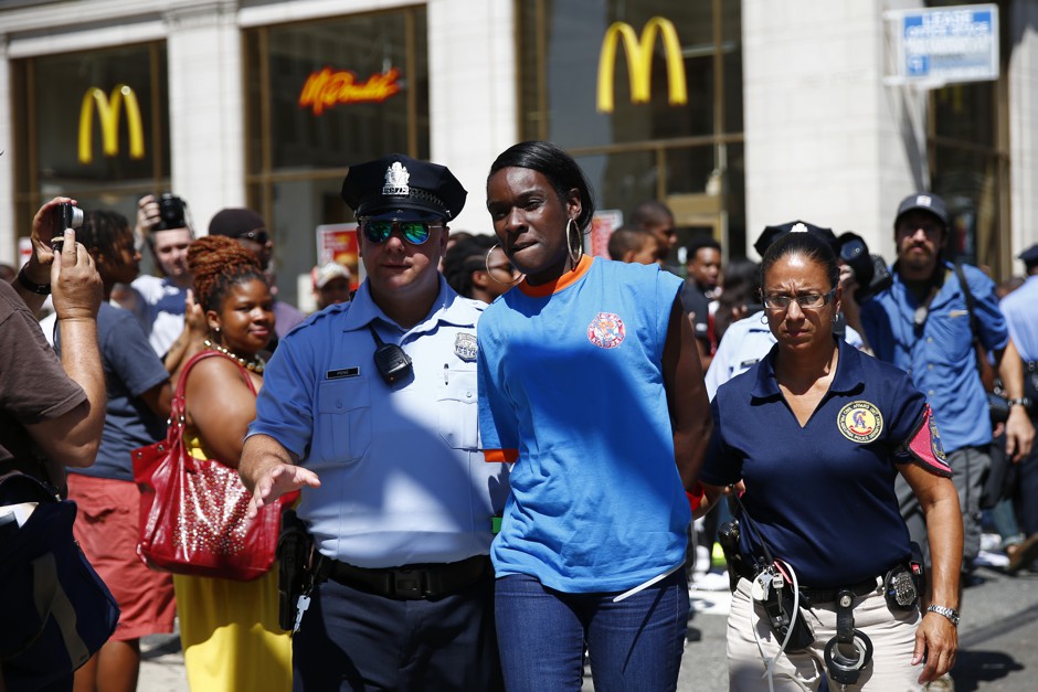 A fast-food worker is detained by police during a protest to push fast-food chains to pay their employees at least $15 an hour, outside a McDonald's restaurant Thursday, Sept. 4, 2014, in Philadelphia.