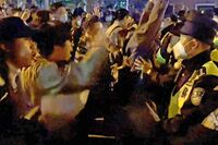 A video grab shows demonstrators shouting slogans as police hold their positions, in Shanghai on Nov. 27.