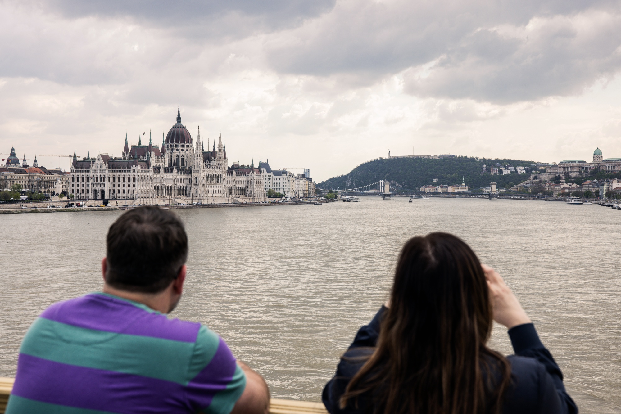 Tourists look across the River Danube at the Hungarian Parliament building in Budapest, Hungary.